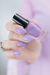 Woman hand with long nails manicure and light pink lilac nail polish