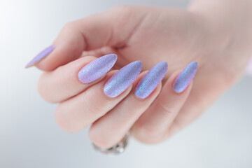 Woman hand with long nails manicure and light pink lilac nail polish