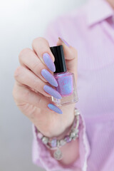 Woman hand with long nails manicure and light pink lilac nail polish