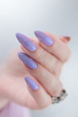 Woman hands with long nails manicure and light blue lilac pink nail polish