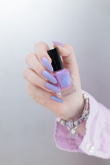 Woman hand with long nails manicure and light pink lilac nail polish