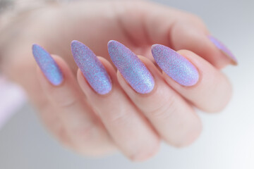 Woman hand with long nails manicure and light pink lilac nail polish