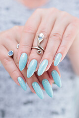 Woman's beautiful hand with long nails and light baby blue manicure