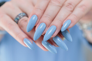 Woman's beautiful hand with long nails and light baby blue manicure
