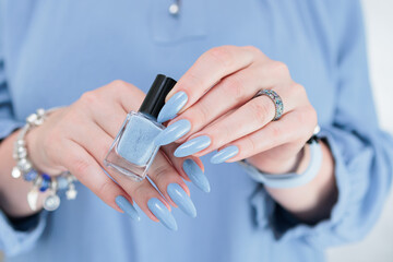 Woman's beautiful hand with long nails and light baby blue manicure