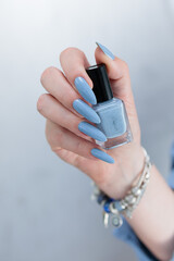 Woman's beautiful hand with long nails and light baby blue manicure	