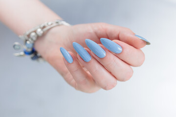 Woman's beautiful hand with long nails and light baby blue manicure	