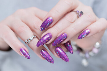 Fototapeta premium Woman hand with long nails and a bottle of plum purple nail polish