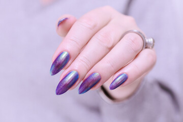 beautiful female hand with long nails, purple and blue manicure 