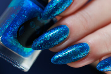 Woman's beautiful hand with long nails and bright blue green manicure