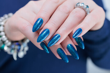 Woman's beautiful hand with long nails and bright blue manicure