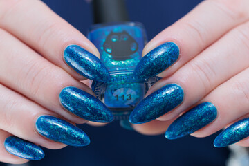Woman's beautiful hand with long nails and bright blue manicure