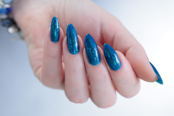 Woman's beautiful hand with long nails and blue and green manicure	