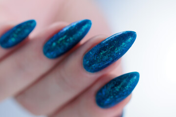 Woman's beautiful hand with long nails and bright blue manicure 