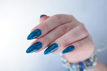 Woman's beautiful hand with long nails and bright blue manicure 
