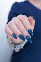 Woman's beautiful hand with long nails and bright blue manicure 