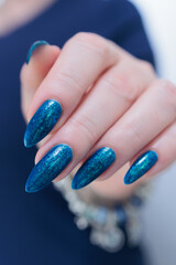 Woman's beautiful hand with long nails and bright blue manicure 