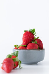 Fresh strawberries in ceramic bowl on white background