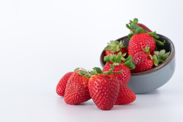 Fresh strawberries in ceramic bowl on white background