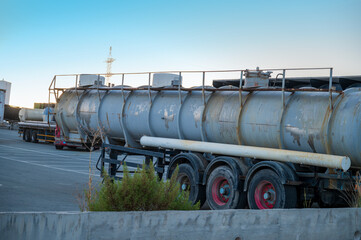 Various types of trucks parked in a large parking area, with assorted truck parts.
