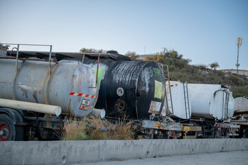 Various types of trucks parked in a large parking area, with assorted truck parts.
