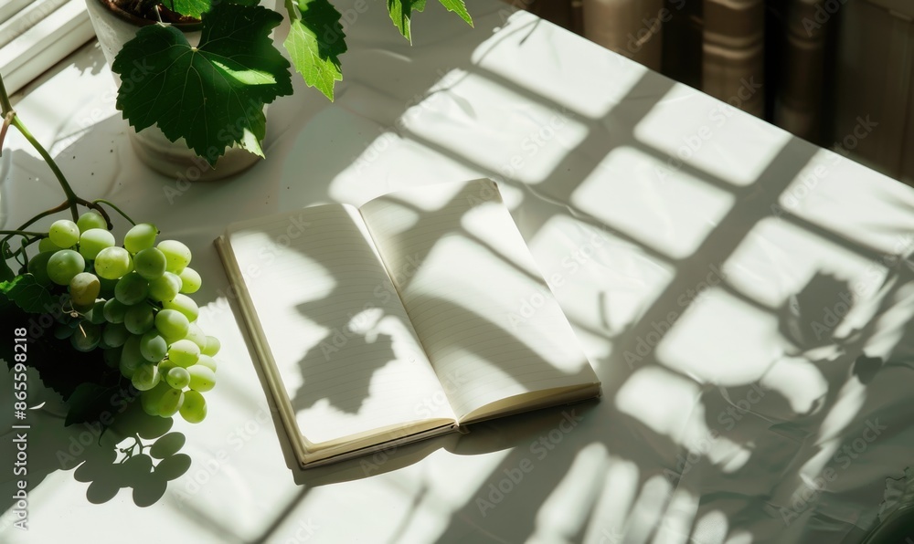 Poster closed notebook on a white table with a bunch of grapes