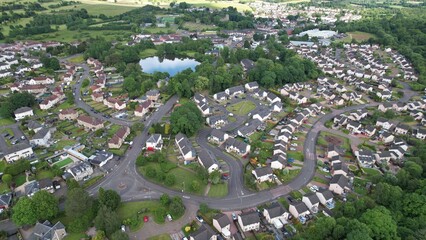 Low level aerial footage over the rural village of Lennoxtown in Central Scotland with village pond and range of hills in background.