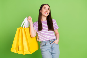 Photo of lovely young lady look empty space hold shopping bags dressed stylish striped violet...