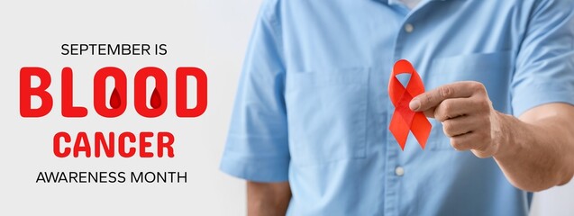 Man with red ribbon on light background, closeup. Banner for Blood Cancer Awareness Month