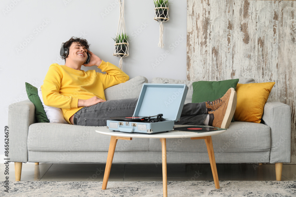 Sticker young man in headphones with record player at home