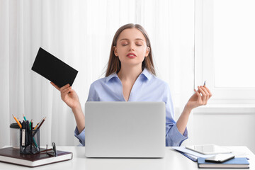 Young businesswoman with notebook meditating in office. Balance concept