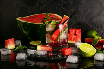 Glass of fresh watermelon lemonade with lime and mint on black background