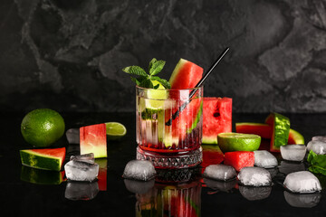 Glass of fresh watermelon lemonade with lime and mint on black background