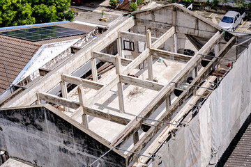 Abandoned concrete building under construction with old architectural features, set against a clear sky in an urban environment. The roof of the house has solar panels installed to use clean energy.