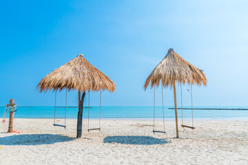Beautiful swings under Nipa palm umbrella and beach with white sand of the sea on the beach blue sky with clouds on a hot sunny day background ,travel summer holiday Thailand