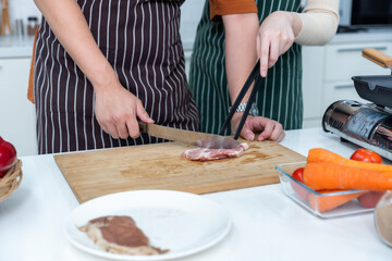 close up hand loving young asian of having fun standing a cheerful preparing food and enjoy cook steak cooking and vegetables, meat, bread while standing on a kitchen Condo life or home