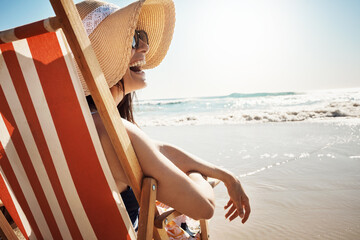 Woman, laugh and sunglasses at beach with water, sand and relax for vacation by ocean in summer....