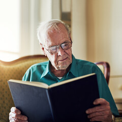 Elderly man, study and reading book in home, literature and language for learning in retirement. Old person, fiction and textbook for knowledge to relax, glasses and fantasy story or information