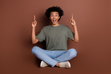 Full body photo of attractive young man sit floor point up empty space dressed stylish khaki...