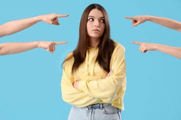 People pointing at young woman on blue background. Accusation concept