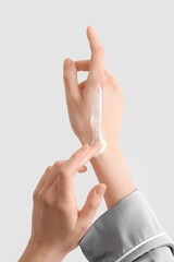 Woman applying cream onto her hands against light background, closeup