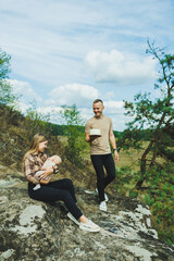 A young married couple with a small child in their arms in nature. Rest of mom, dad and their newborn son in nature.