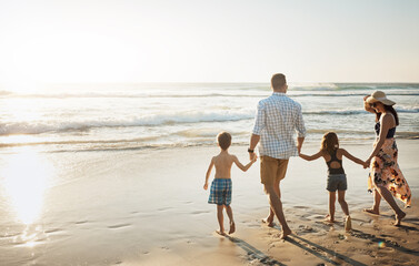 Back, walking and holding hands with family on beach for summer holiday, weekend or bonding together in nature. Mother, father and children strolling on ocean coast for outdoor vacation in sunshine