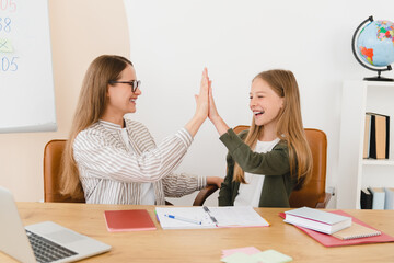 Successful young tutor teacher mother babysitter nanny helping her daughter student schoolgirl with...