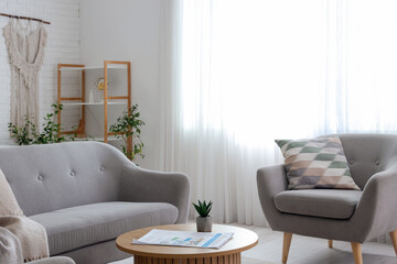 Interior of white living room with grey sofa, shelving unit and coffee table