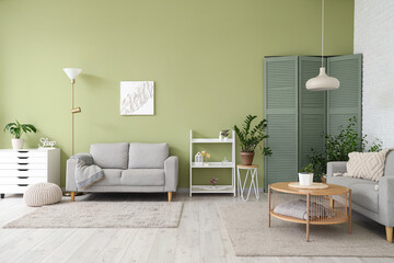 Stylish interior of living room with comfortable sofa, houseplants and chest of drawers