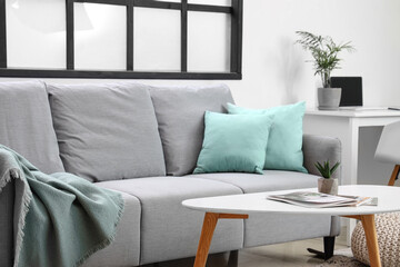 Stylish interior of light living room with sofa, cushions and coffee table