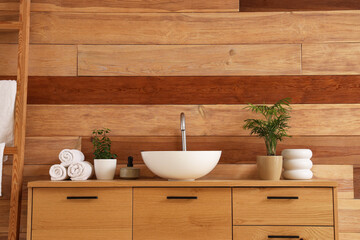 Stylish cabinet with washbasin near wooden wall in bathroom