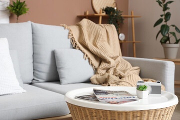 Stylish interior of living room with cozy sofa, pillows, coffee table and plaid, closeup