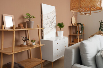 Interior of living room with sofa, pillow, chest of drawers, shelving unit and picture